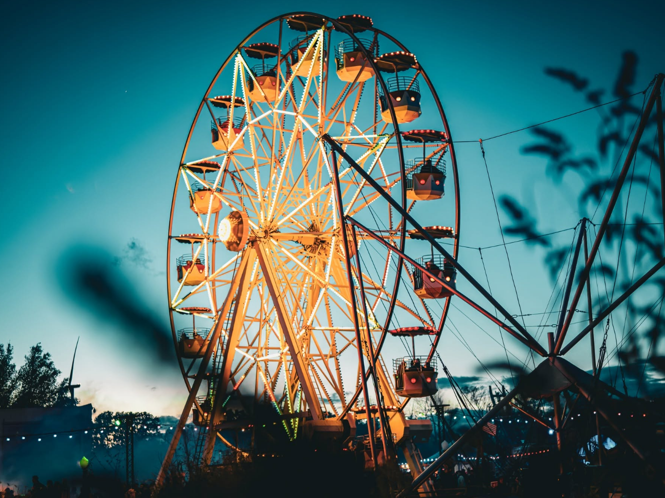 Ein beleuchtetes Riesenrad bei Dämmerung, der Himmel ist blau.