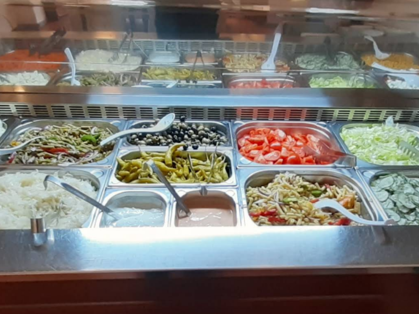 Salatbuffet mit frischem Gemüse, Oliven, Reis und Dressings