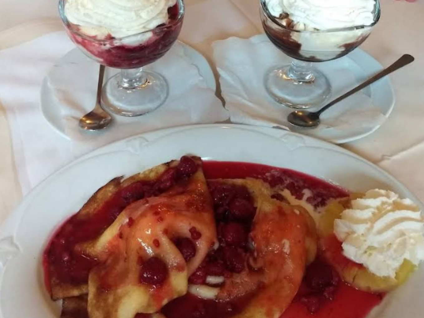 Dessertteller mit Beeren, Fruchtsoße, Eis und Sahne