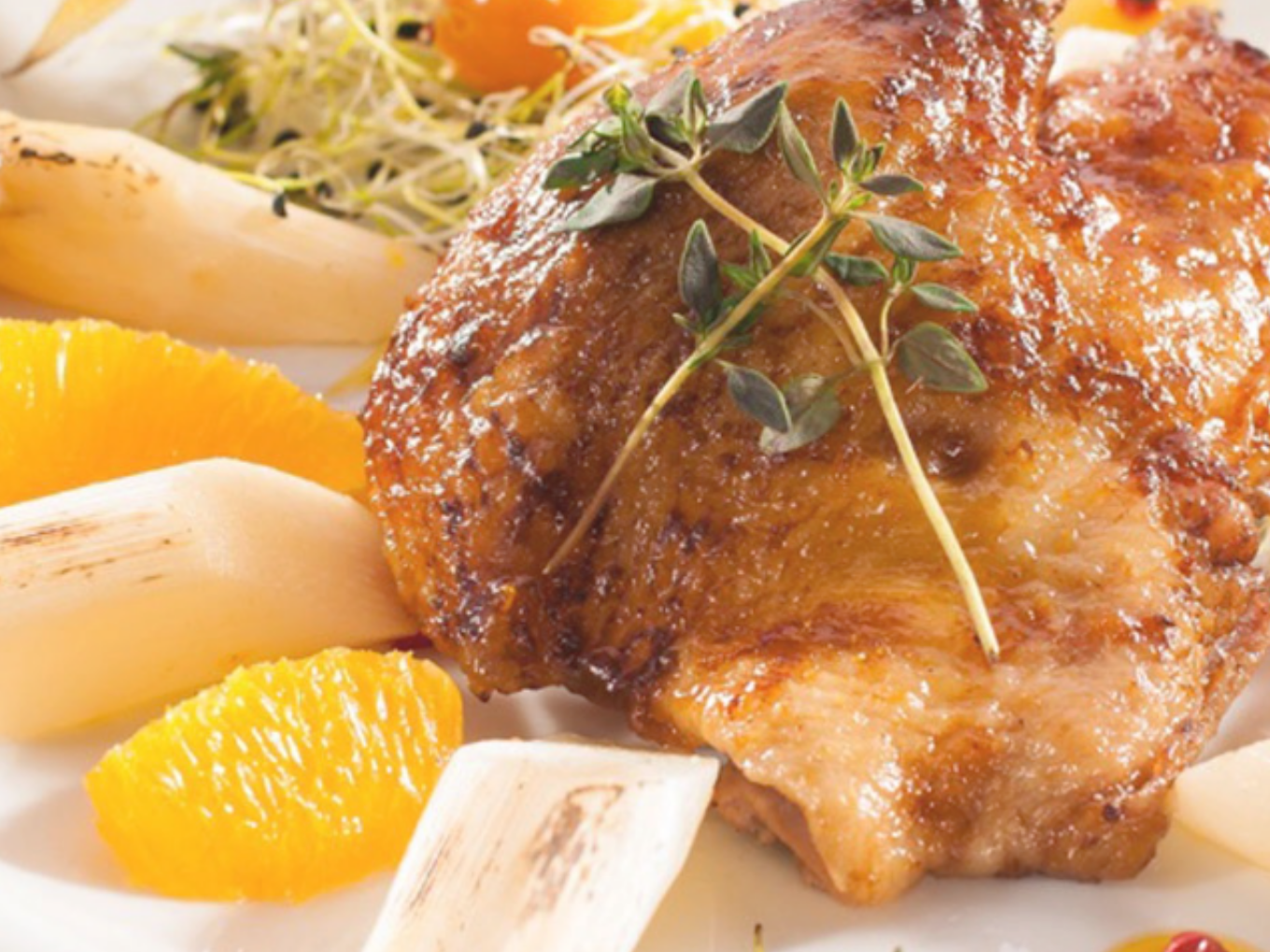 Gebratenes Hähnchenfilet mit Spargel, Orangenstücken und Sprossen.