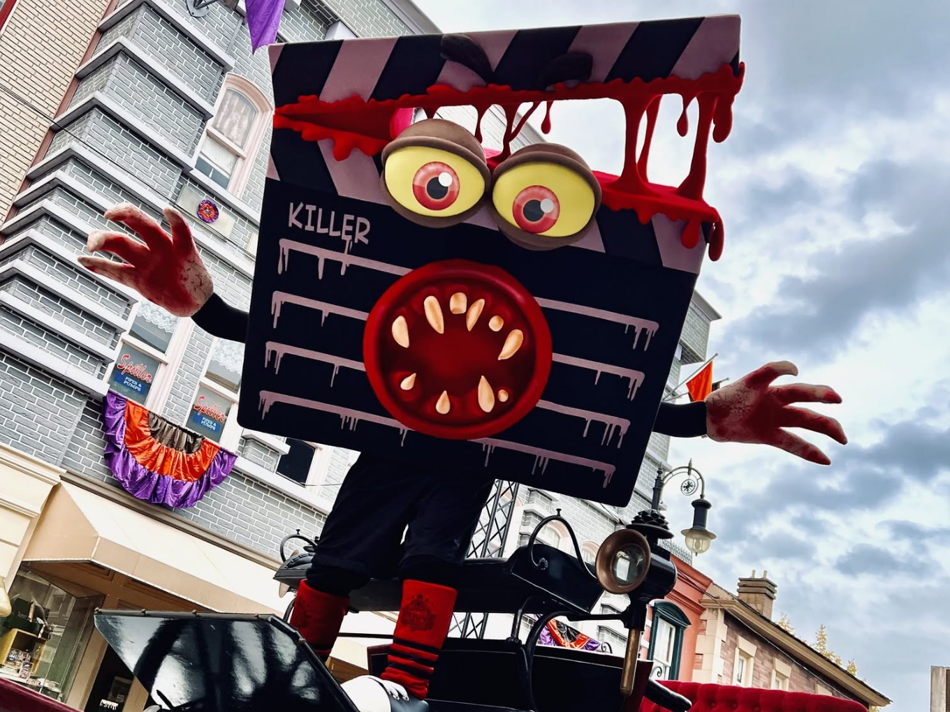 Eine große, gruselige Filmklappe mit Zähnen und blutigen Händen als Kostümfigur auf einer Straße.