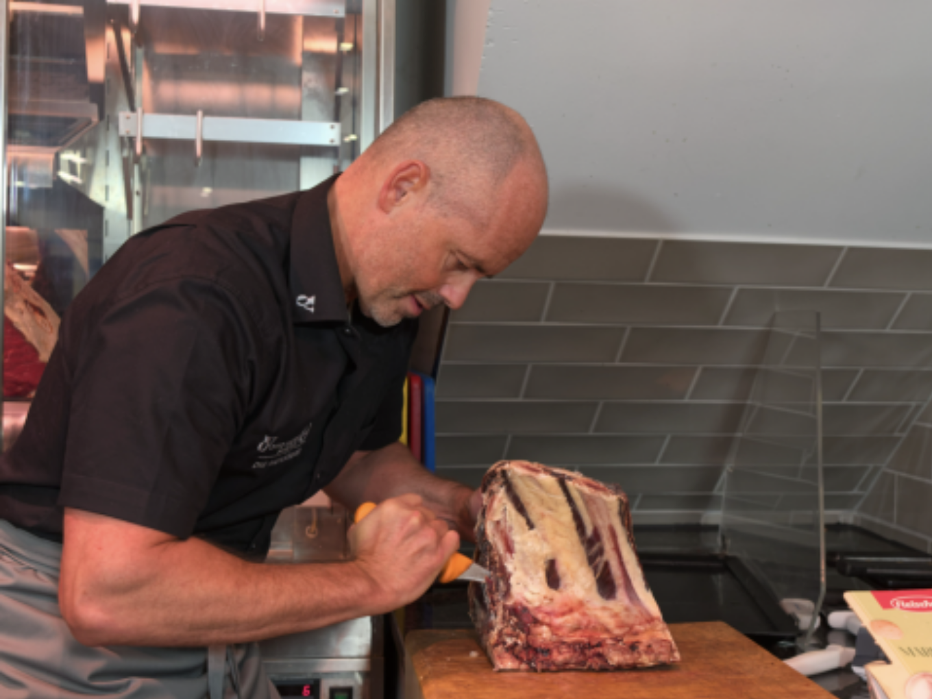 Ein Metzger schneidet ein großes Stück Fleisch auf einem Holzbrett.