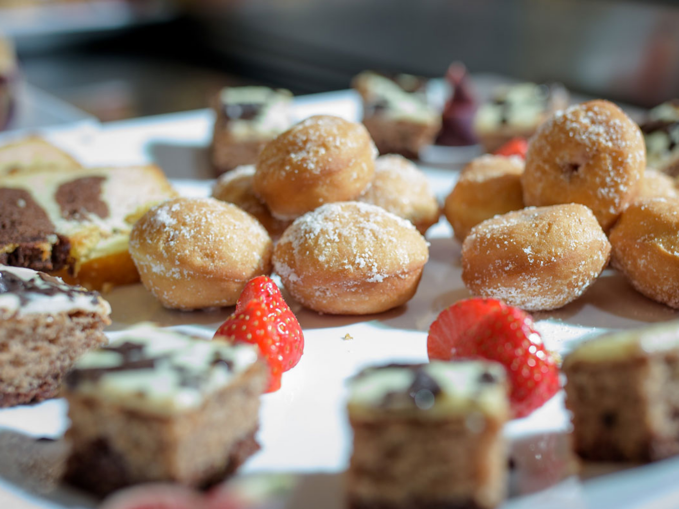 Verschiedene kleine Kuchen und Gebäckstücke mit Erdbeeren auf einem Teller.