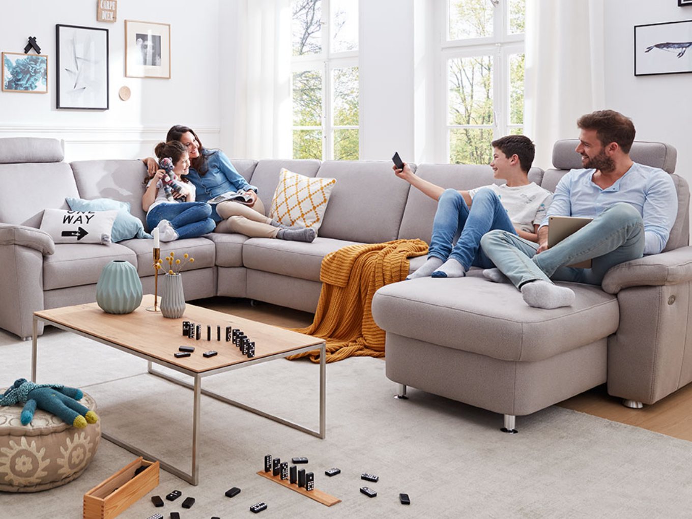 Eine Familie sitzt gemütlich auf einem Sofa im Wohnzimmer und genießt gemeinsame Zeit miteinander.