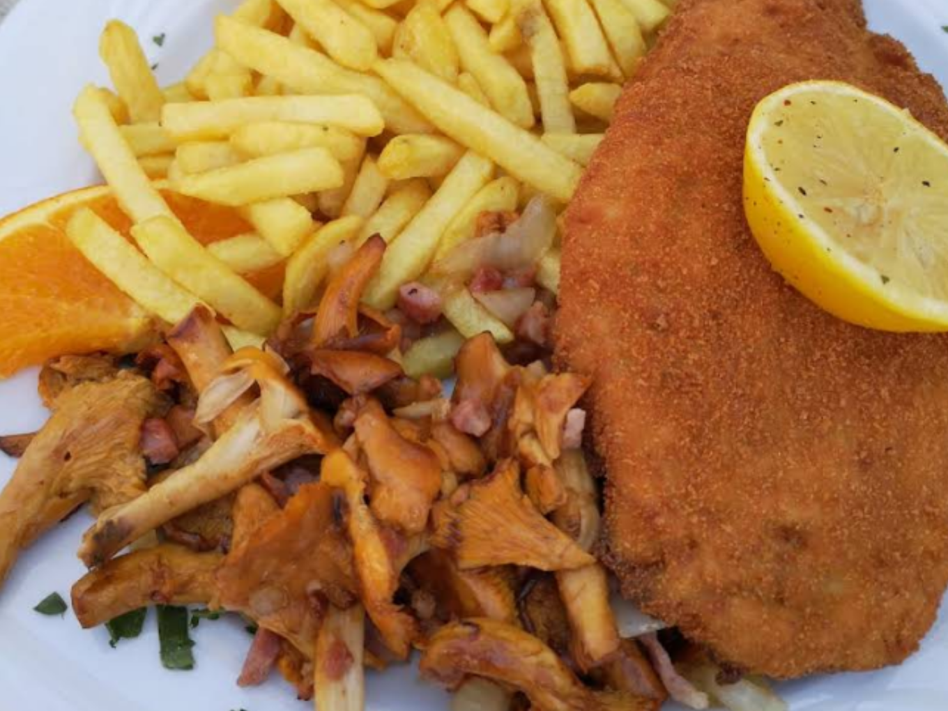 Schnitzel mit Pommes, gebratenen Pfifferlingen und Zitrone