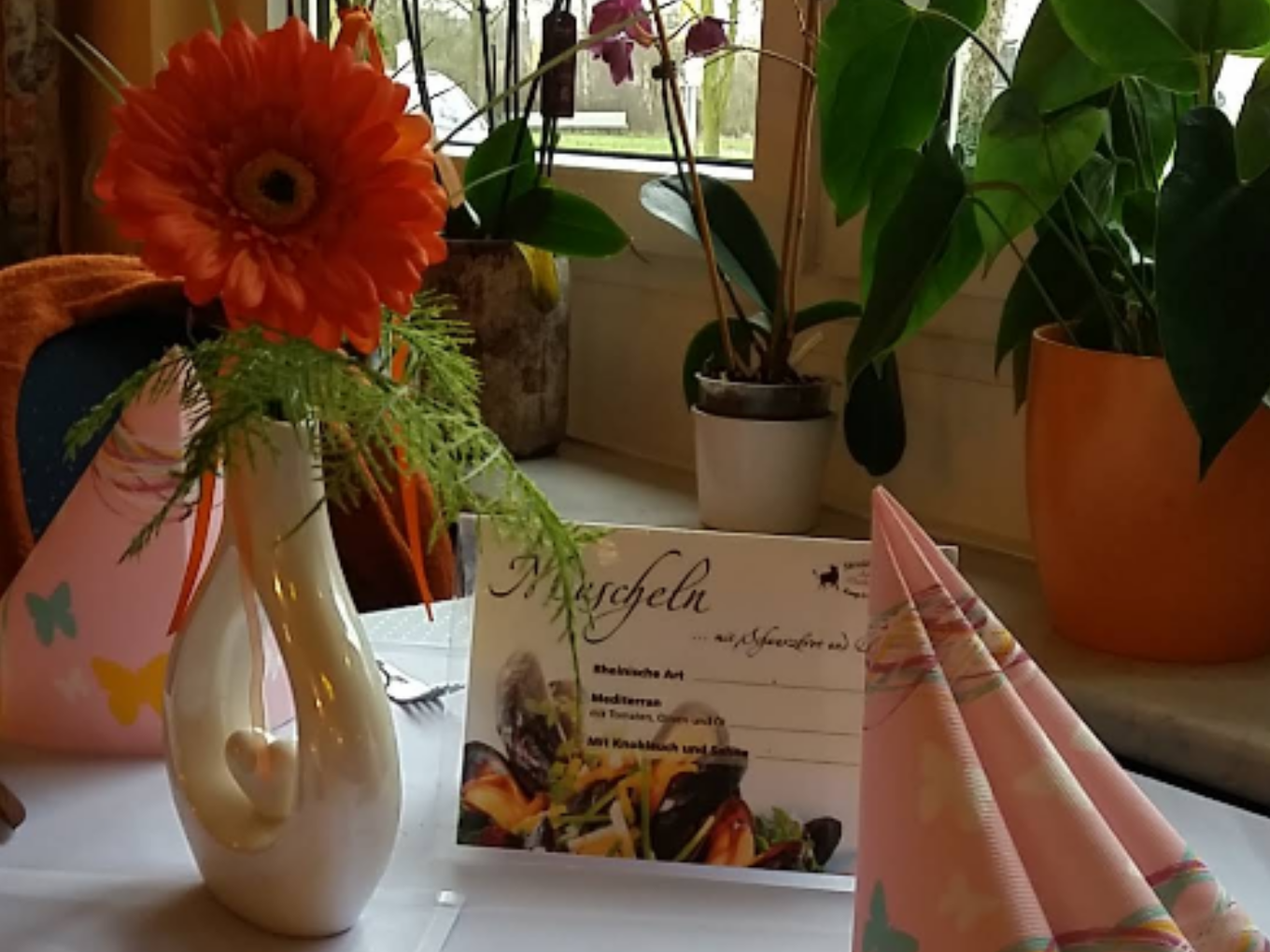 Gedeckter Restauranttisch mit Gerbera und Speisekarte