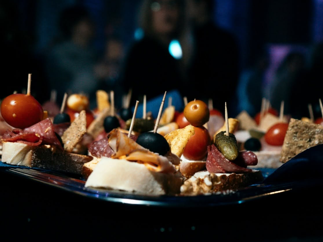 Bunte Canapés mit Tomaten, Oliven und Wurst auf einer Platte bei einer Ü30-Party.