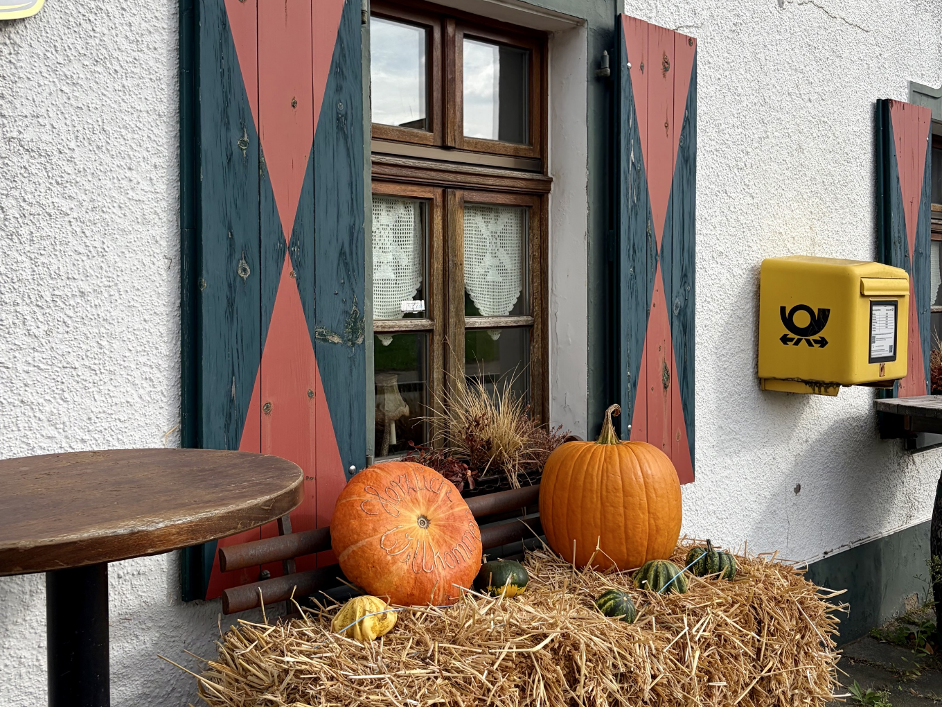 Herbstdekoration mit geschnitzten Kürbissen und Stroh vor einem Restaurant mit Briefkasten