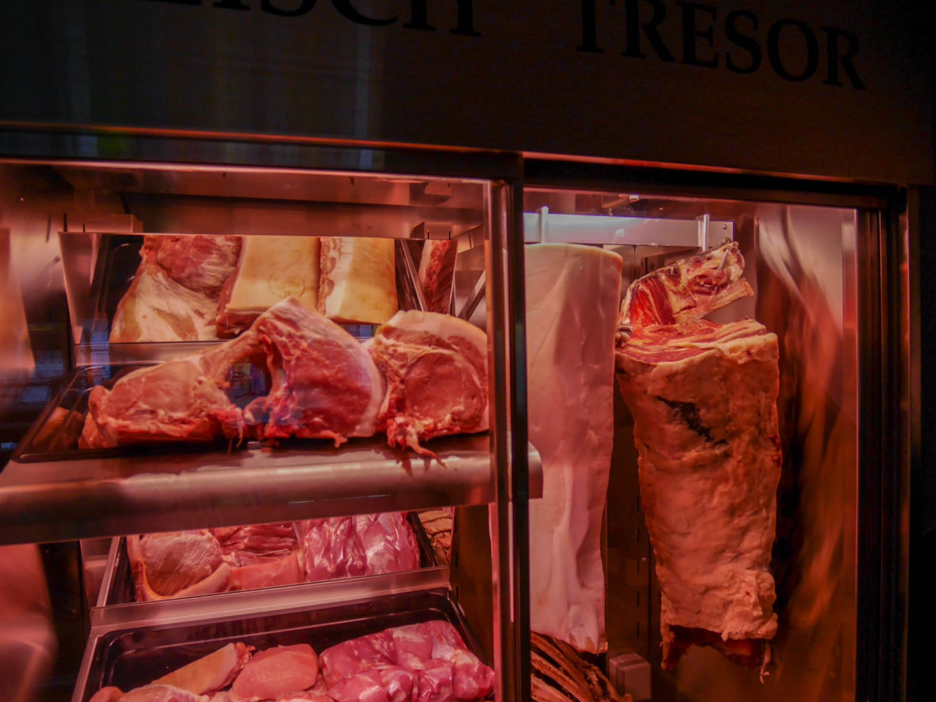 Verschiedene große Fleischstücke in einer gekühlten Vitrine mit der Aufschrift „Fleisch Tresor“.