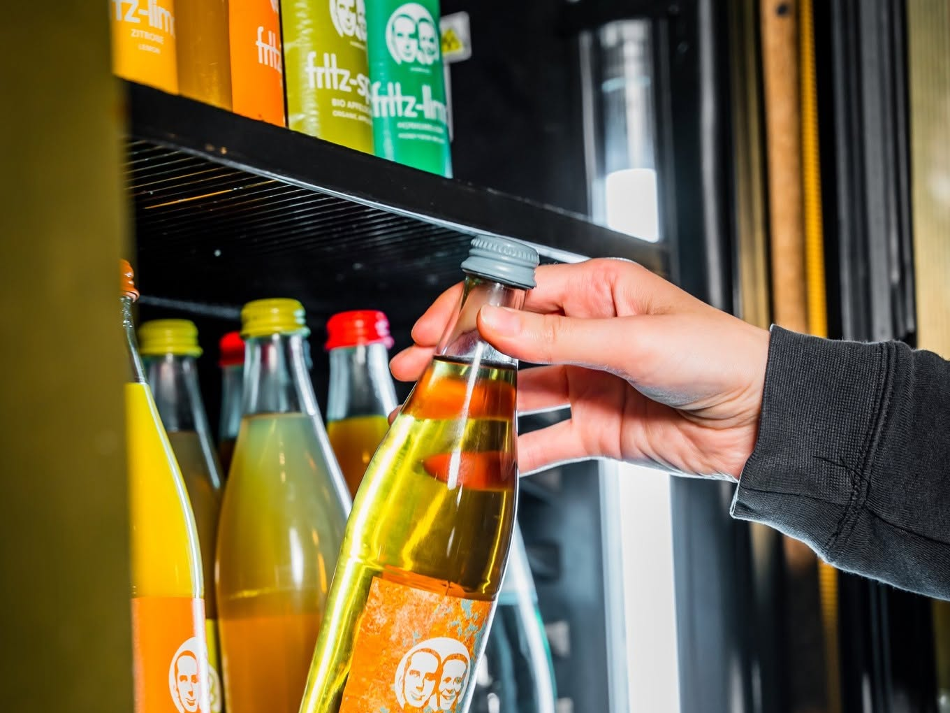 Hand nimmt eine gekühlte Fritz-Limonade aus dem Getränkekühlschrank