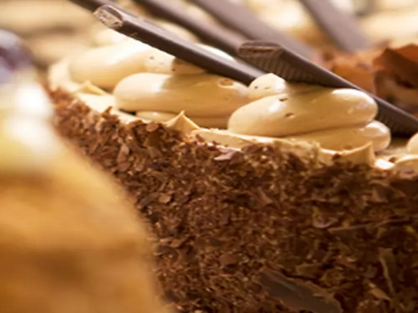 Nahaufnahme einer Schokoladentorte mit heller Creme und Schokoladenstäbchen als Dekoration.