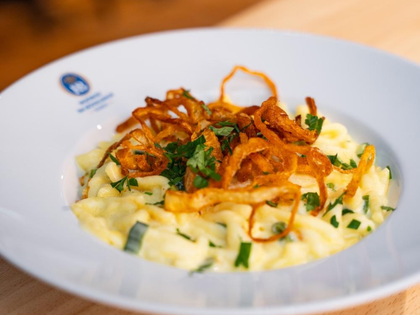 Teller mit Käsespätzle, Röstzwiebeln und Petersilie.