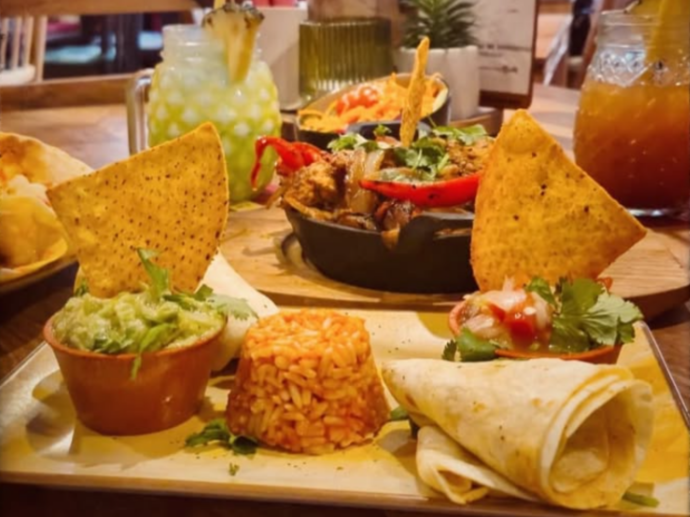 Verschiedene mexikanische Speisen auf einem Teller, darunter Reis, Guacamole, Salsa, Tortilla und Nachos.