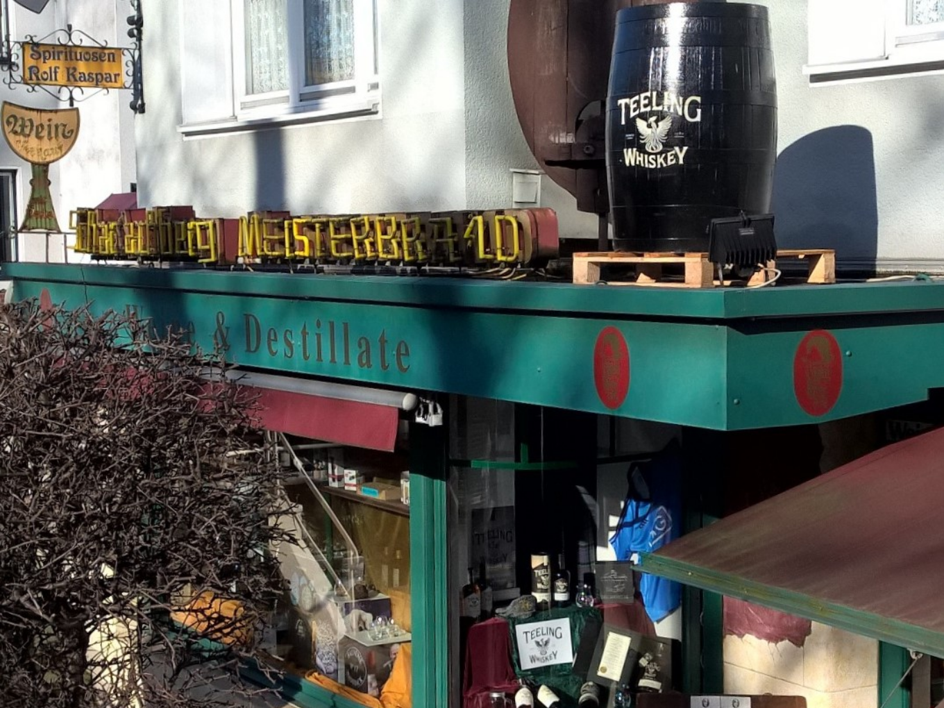 Außenansicht eines Spirituosengeschäfts mit einem großen Whiskyfass auf dem Dach.