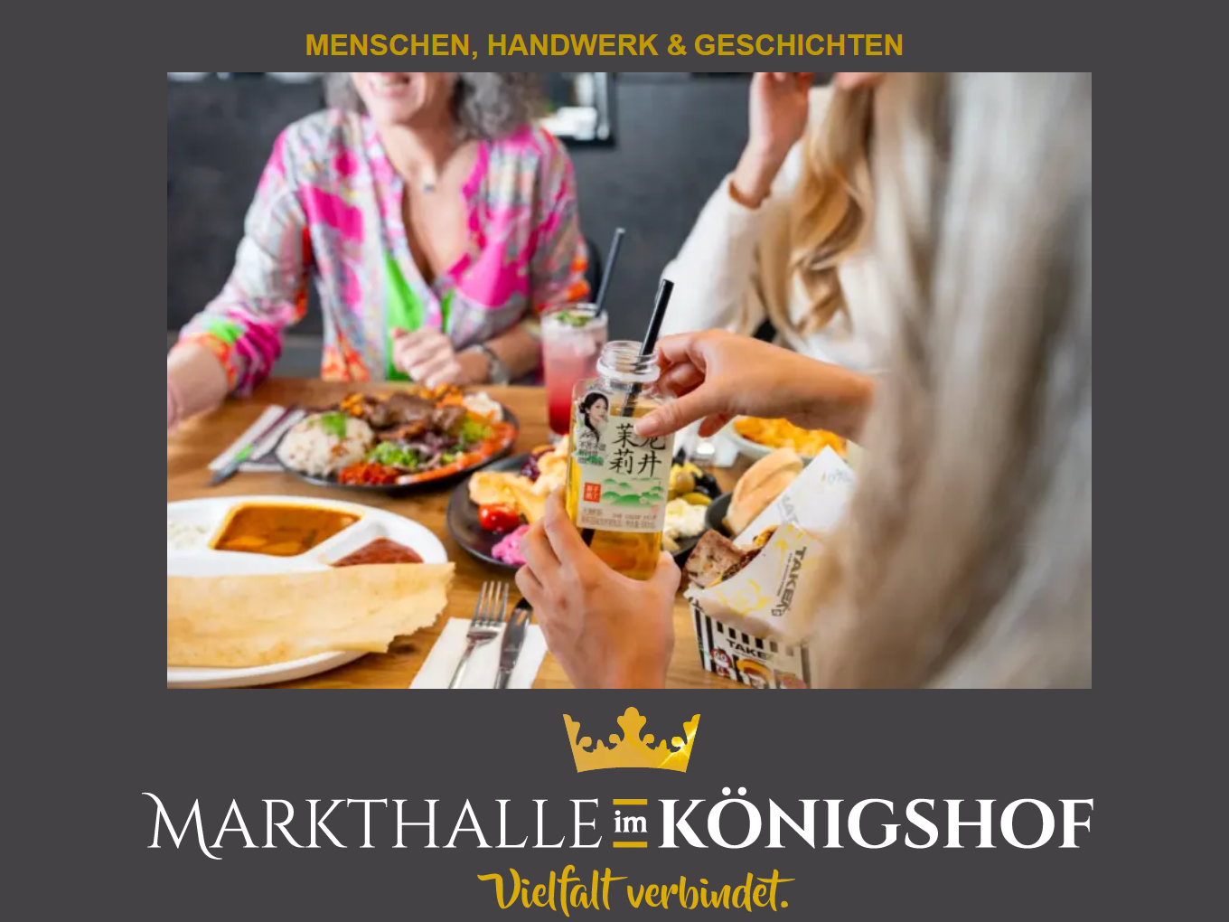 Mehrere Personen essen gemeinsam an einem Tisch in der Markthalle im Königshof; im Vordergrund hält eine Person ein Getränkeglas mit asiatischer Aufschrift.